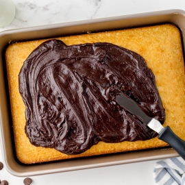 angled frosting a yellow sheet cake with offset spatula