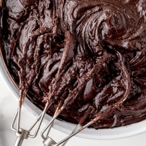 close up beaters in a bowl of chocolate frosting