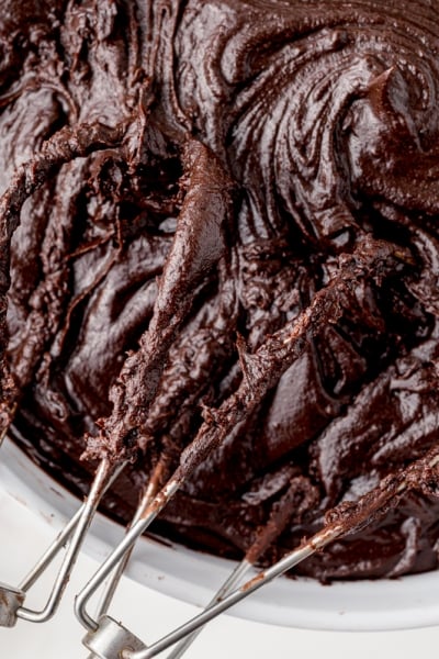 close up beaters in a bowl of chocolate frosting