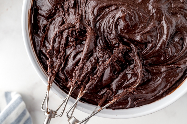 close up beaters in a bowl of chocolate frosting