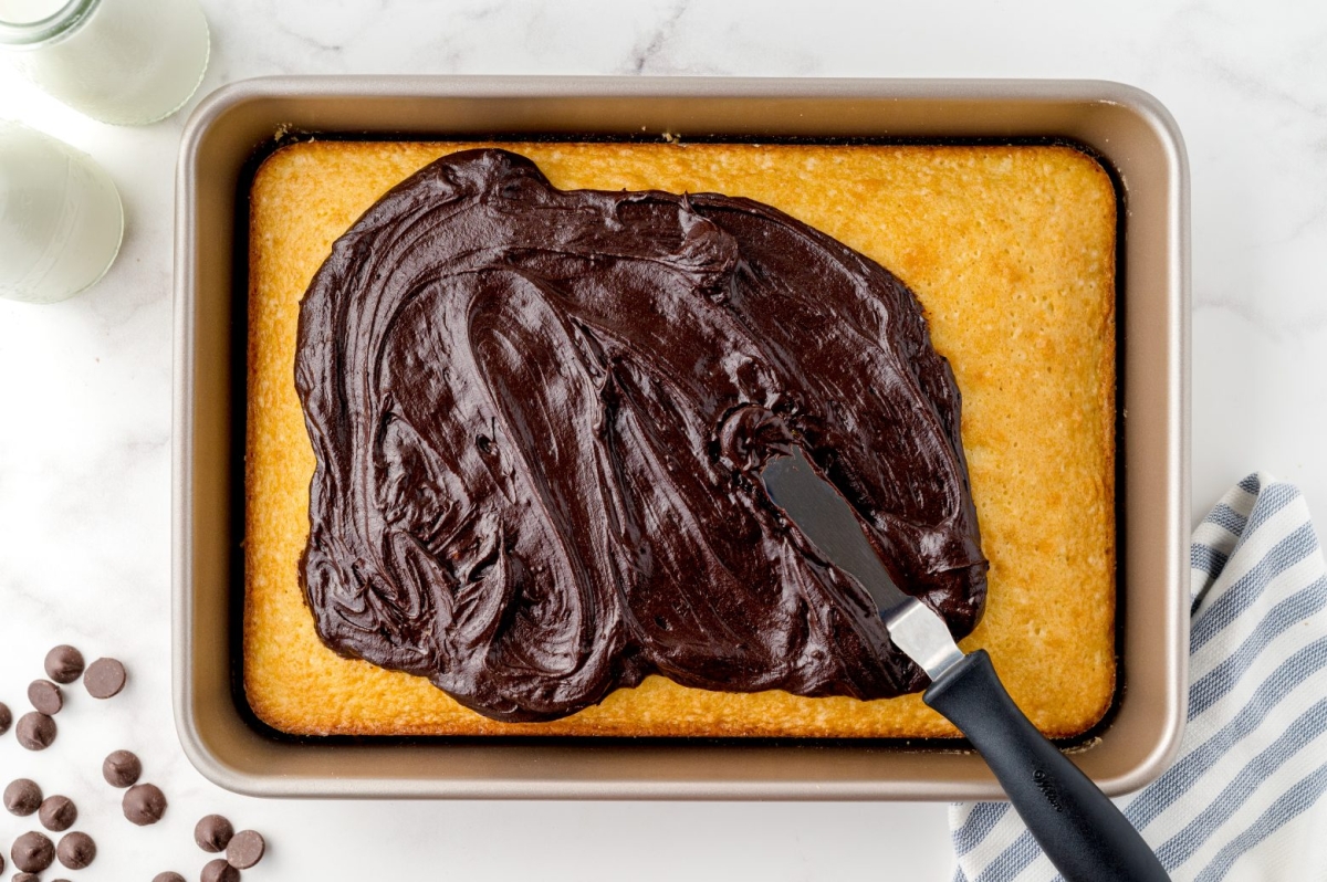 overhead frosting a cake with fudge frosting