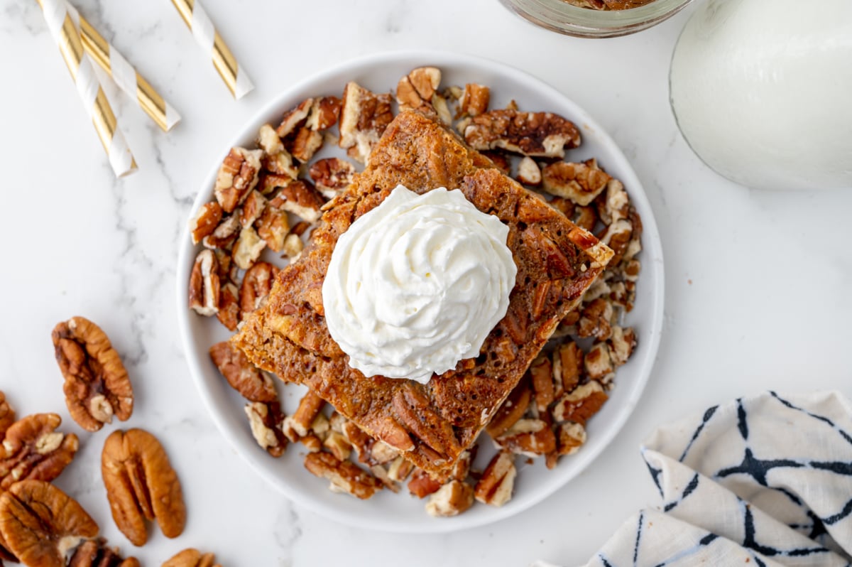 overhead shot of pecan pie bar on plate topped with whipped cream