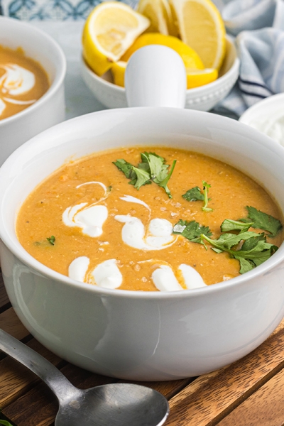 angled shot of bowl of red lentil soup on wooden board