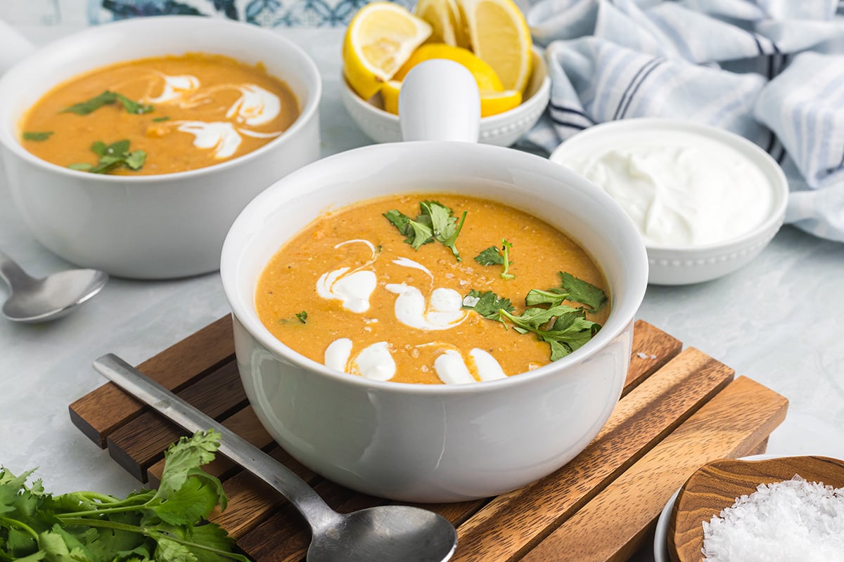 angled shot of bowl of red lentil soup on wooden board