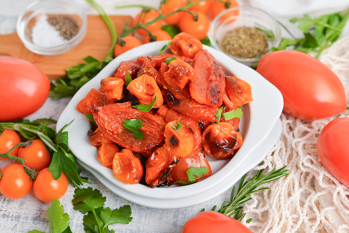 angled shot of oven roasted tomatoes in white bowl