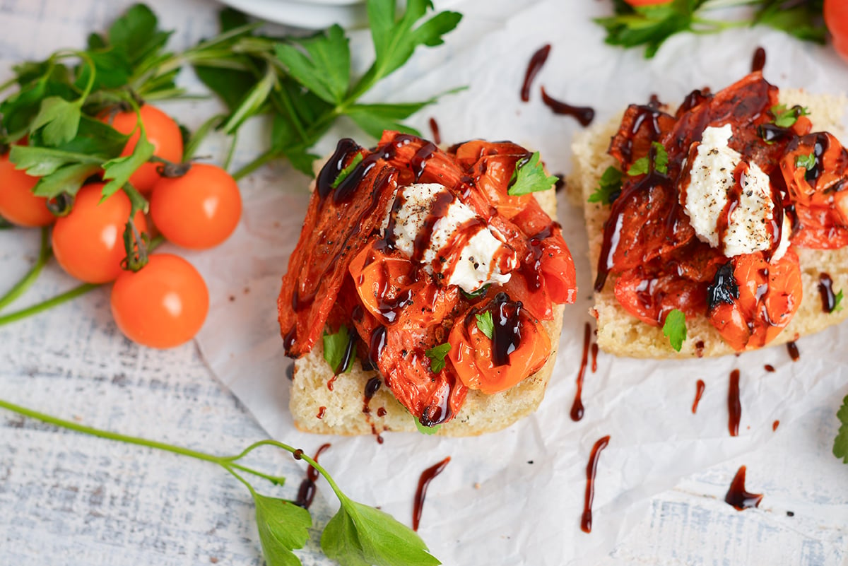angled shot of two crostinis topped with tomatoes, cheese and balsamic