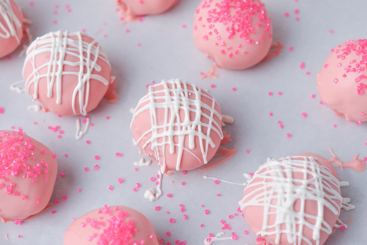 close up angled shot of strawberry cheesecake bites drizzled with white chocolate