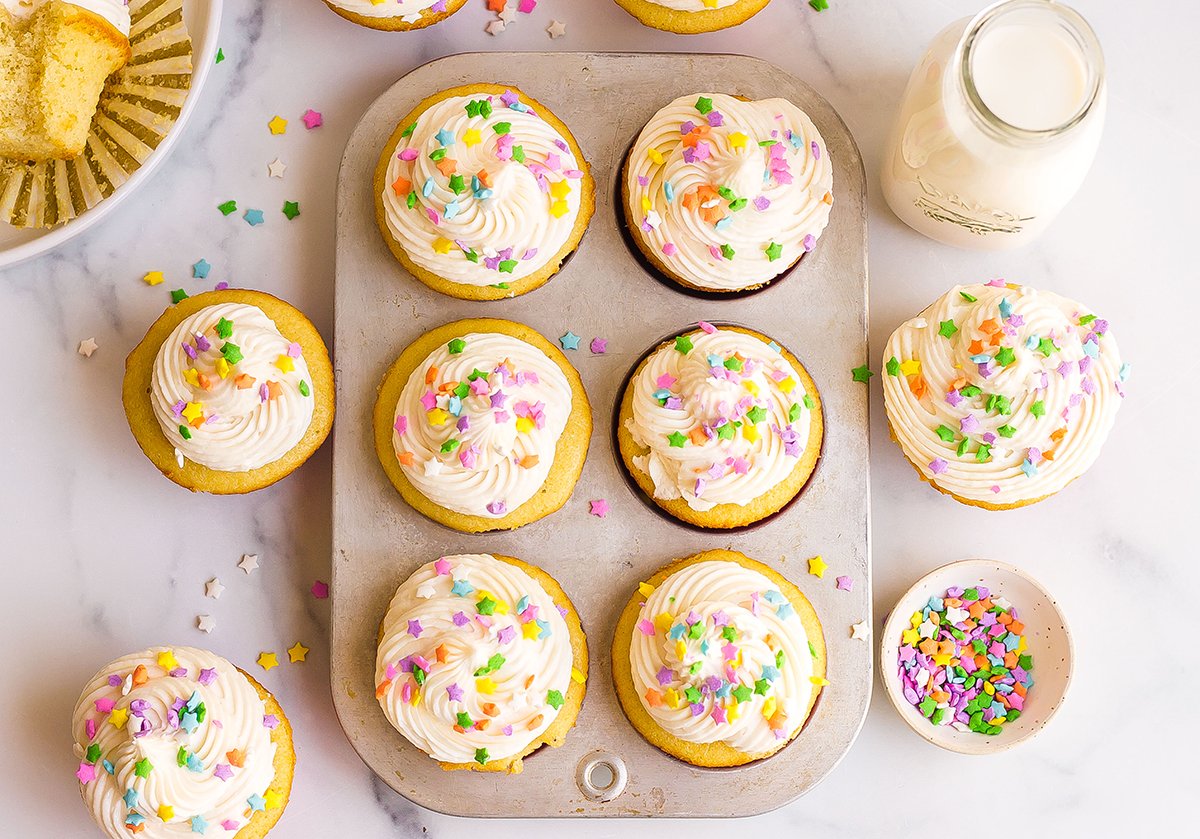 overhead of cupcakes in a 6 cup muffin tin with frosting and spinkles