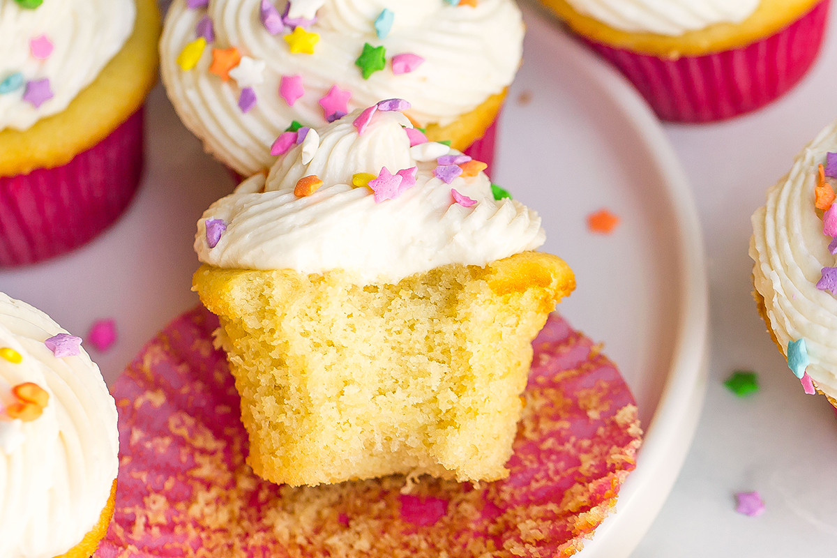 close up of frosted vanilla cupcakes being eaten