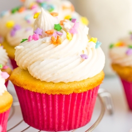 close up of a vanilla cupcake frosted with buttercream and topped with sprinkles