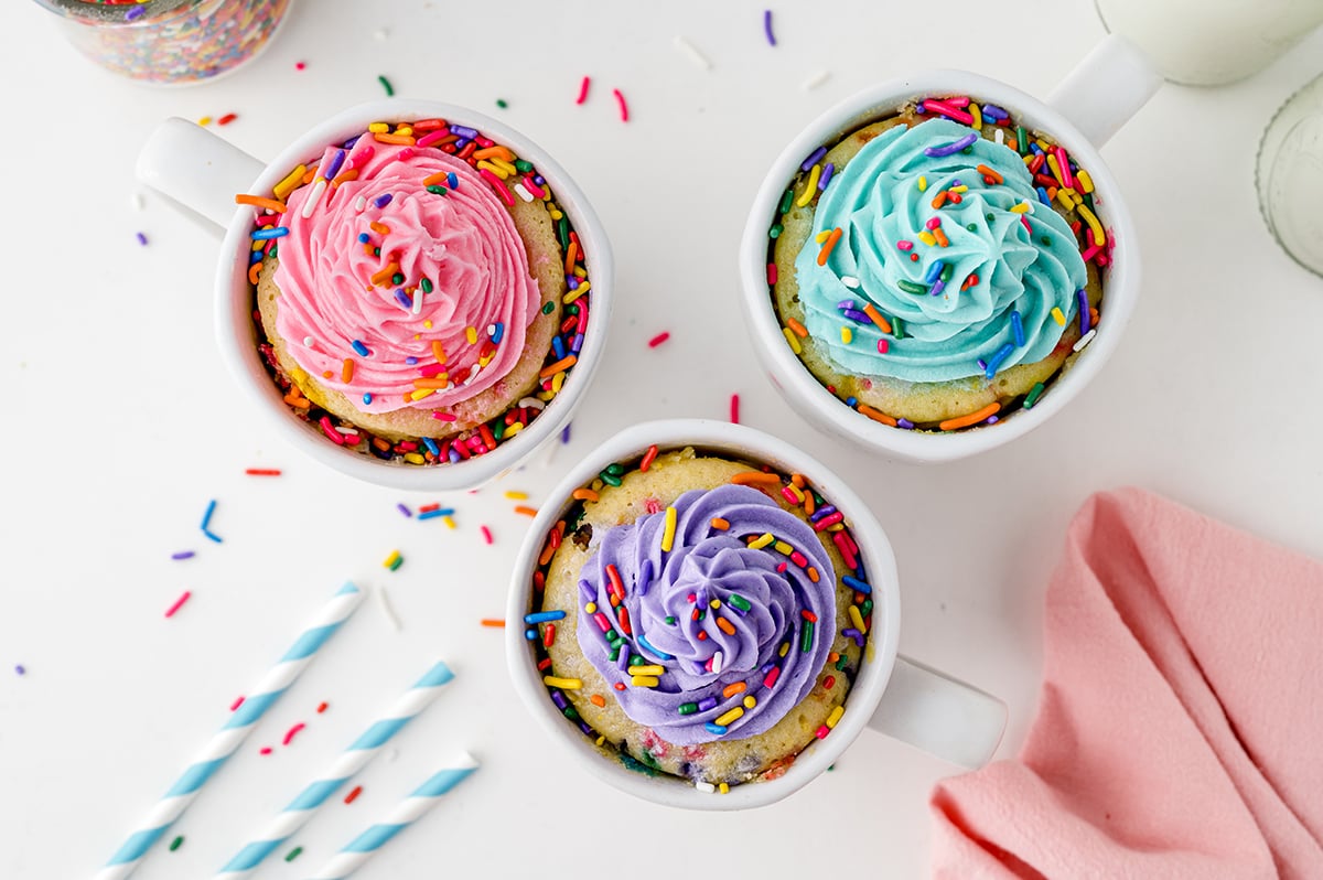 overhead of three vanilla mug cakes with sprinkles and frosting