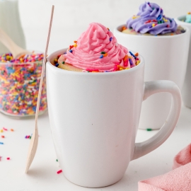 tall coffee mug with cake and frosting and a wooden spoon