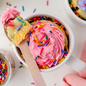 wooden spoon with a bite of rainbow cake and frosting