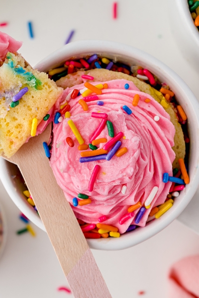 wooden spoon with a bite of rainbow cake and frosting