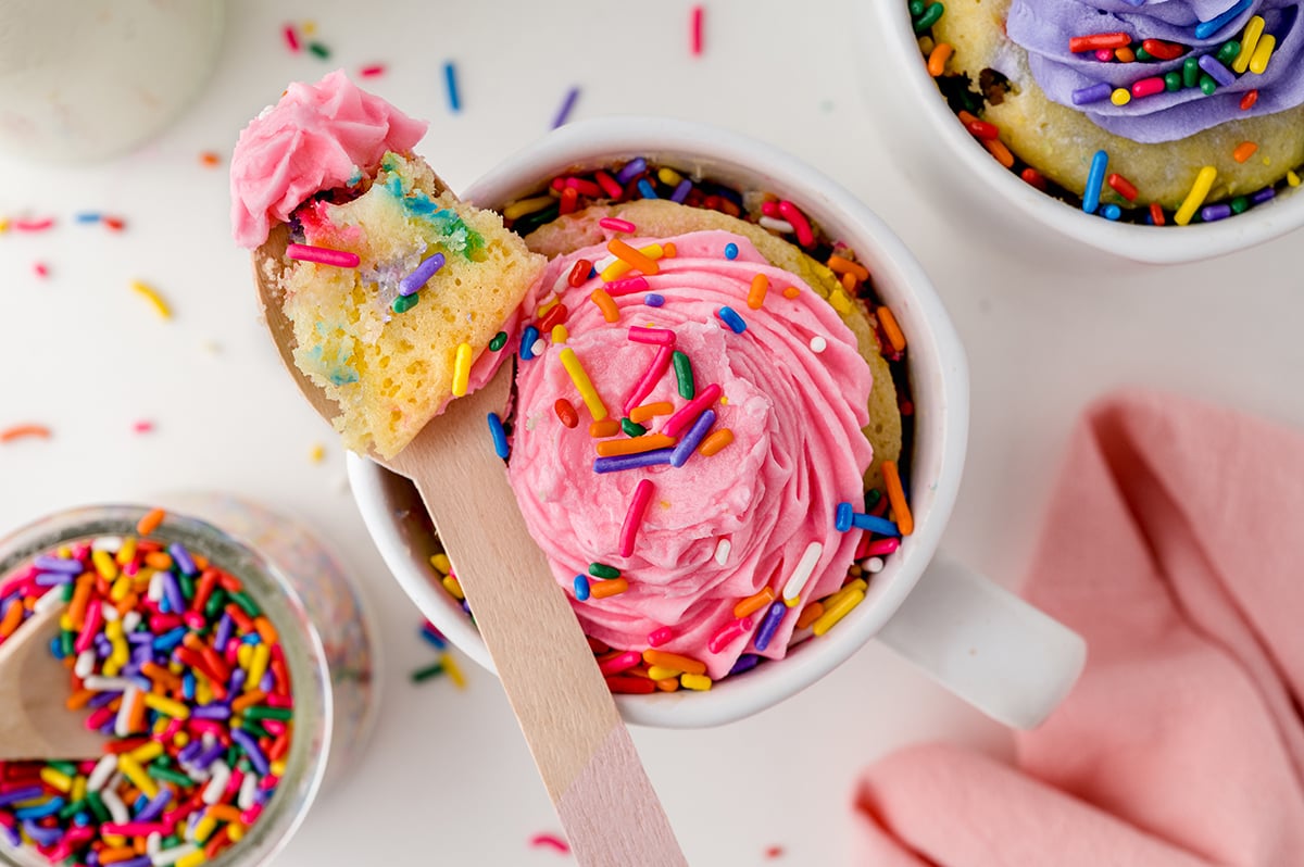 wooden spoon with a bite of rainbow cake and frosting