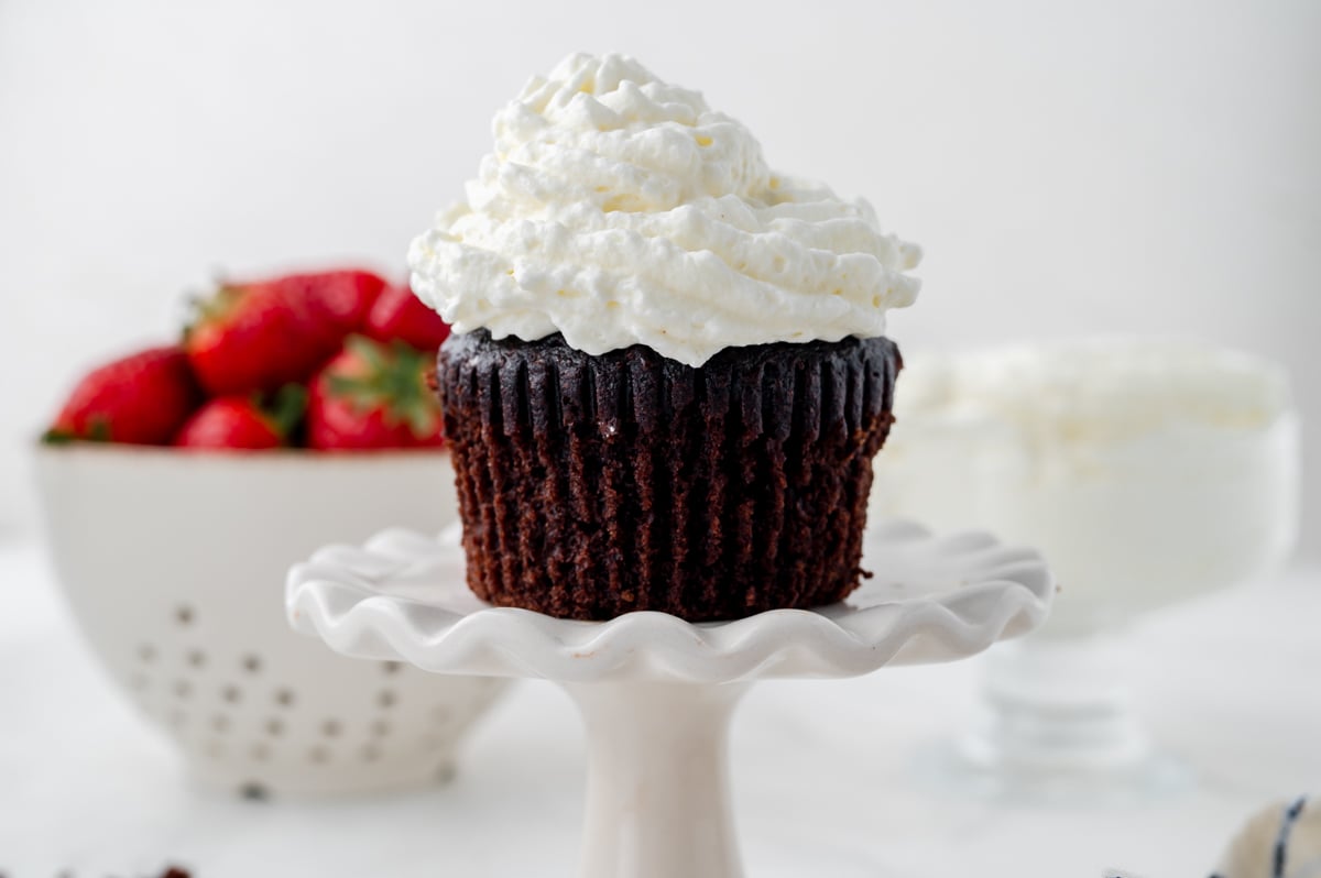 straight on shot of chocolate cupcake topped with homemade whipped cream
