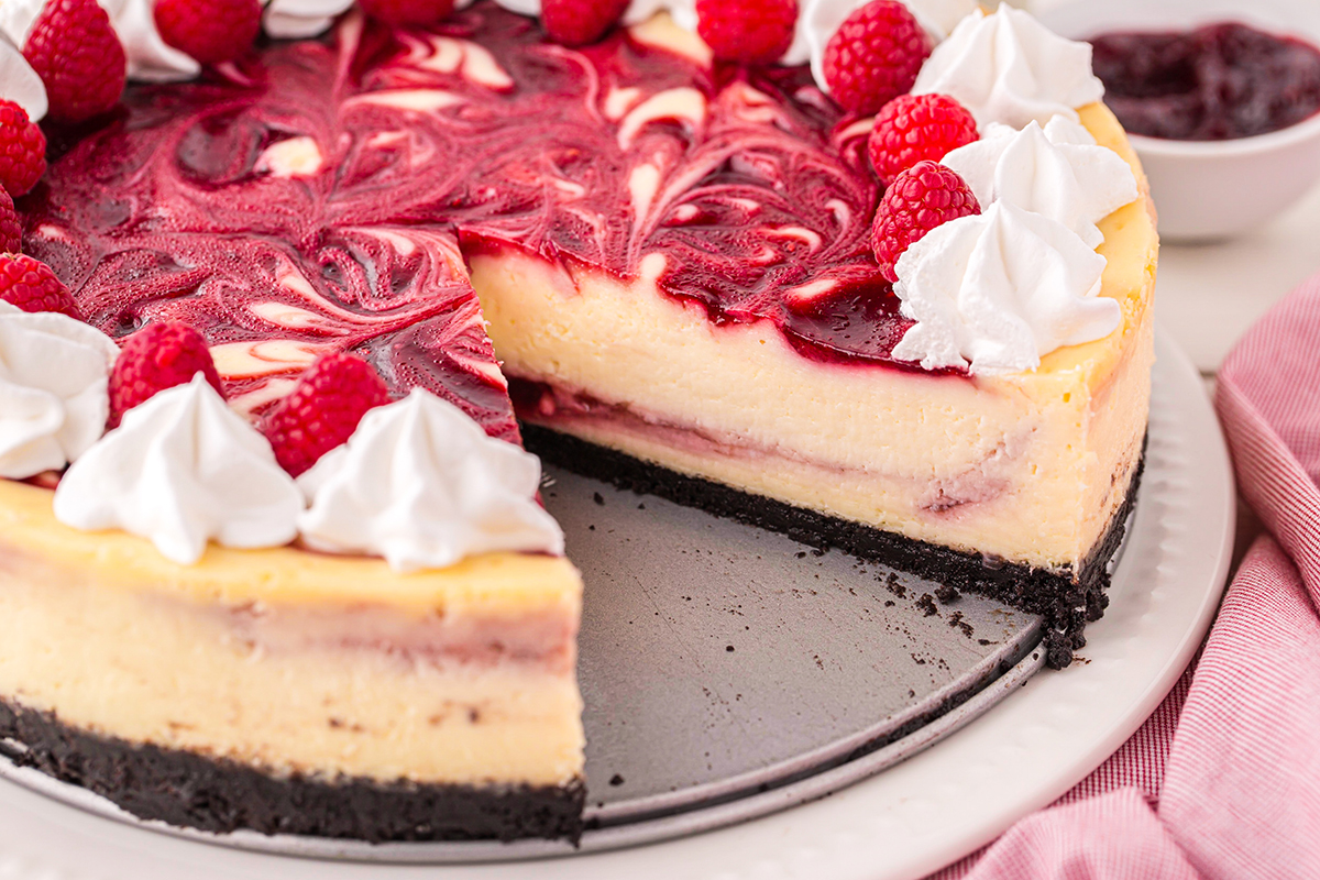 angled shot of slice taken out of raspberry cheesecake