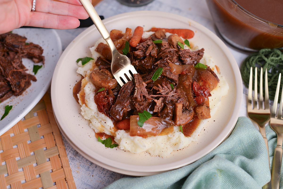 angled shot of fork digging into plate of balsamic slow cooker pot roast