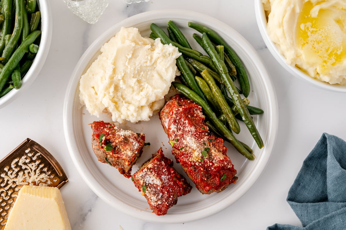 overhead shot of beef braciole on plate with potatoes and green beans