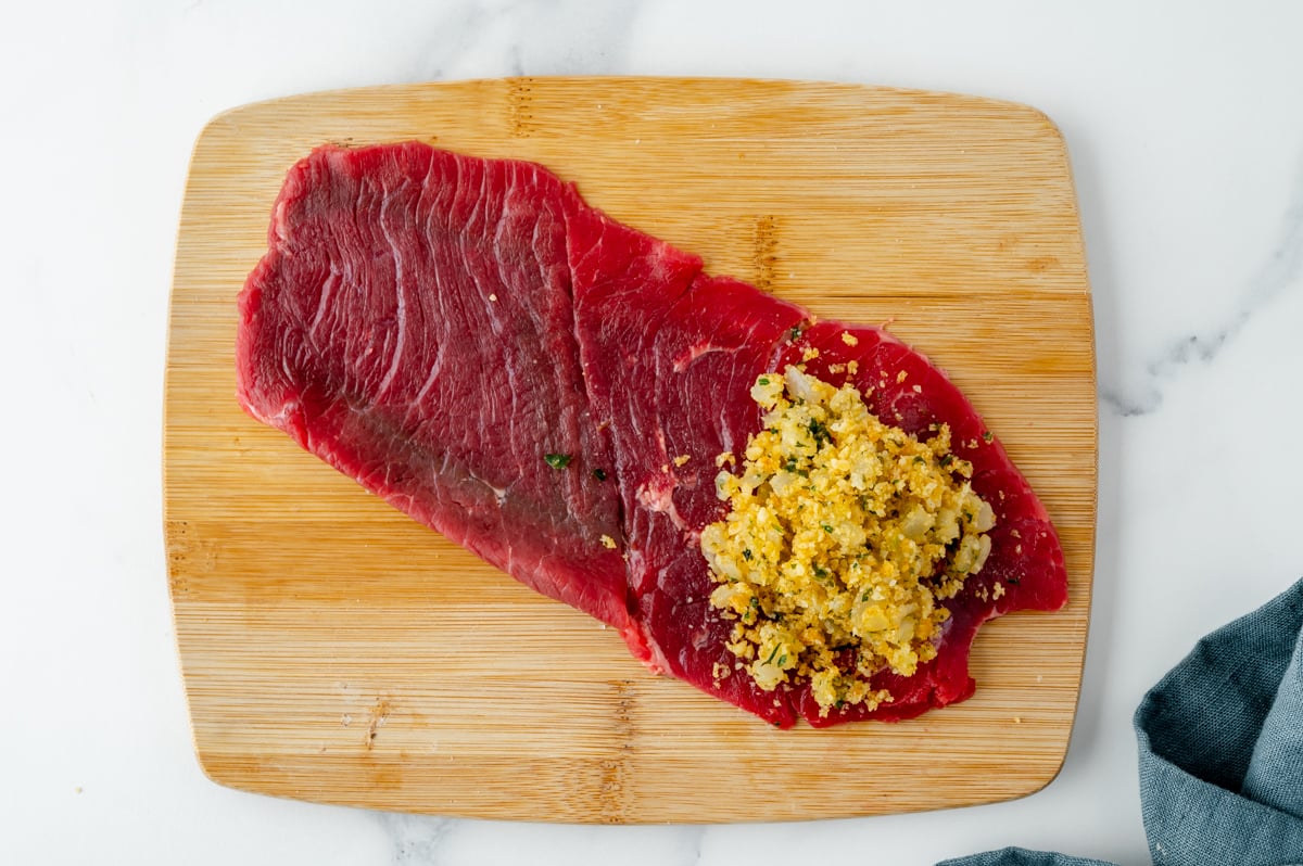 filling added to raw beef on cutting board