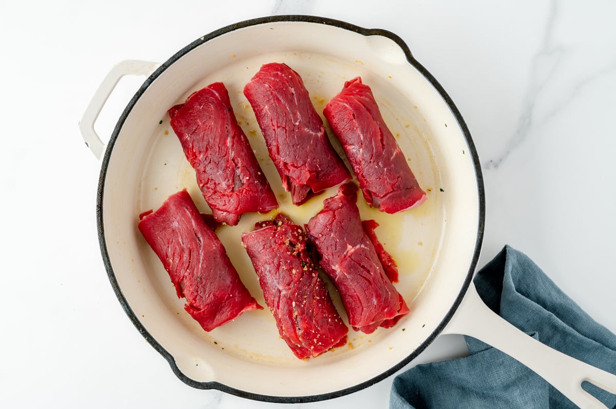 overhead shot of beef braciole cooking in pan