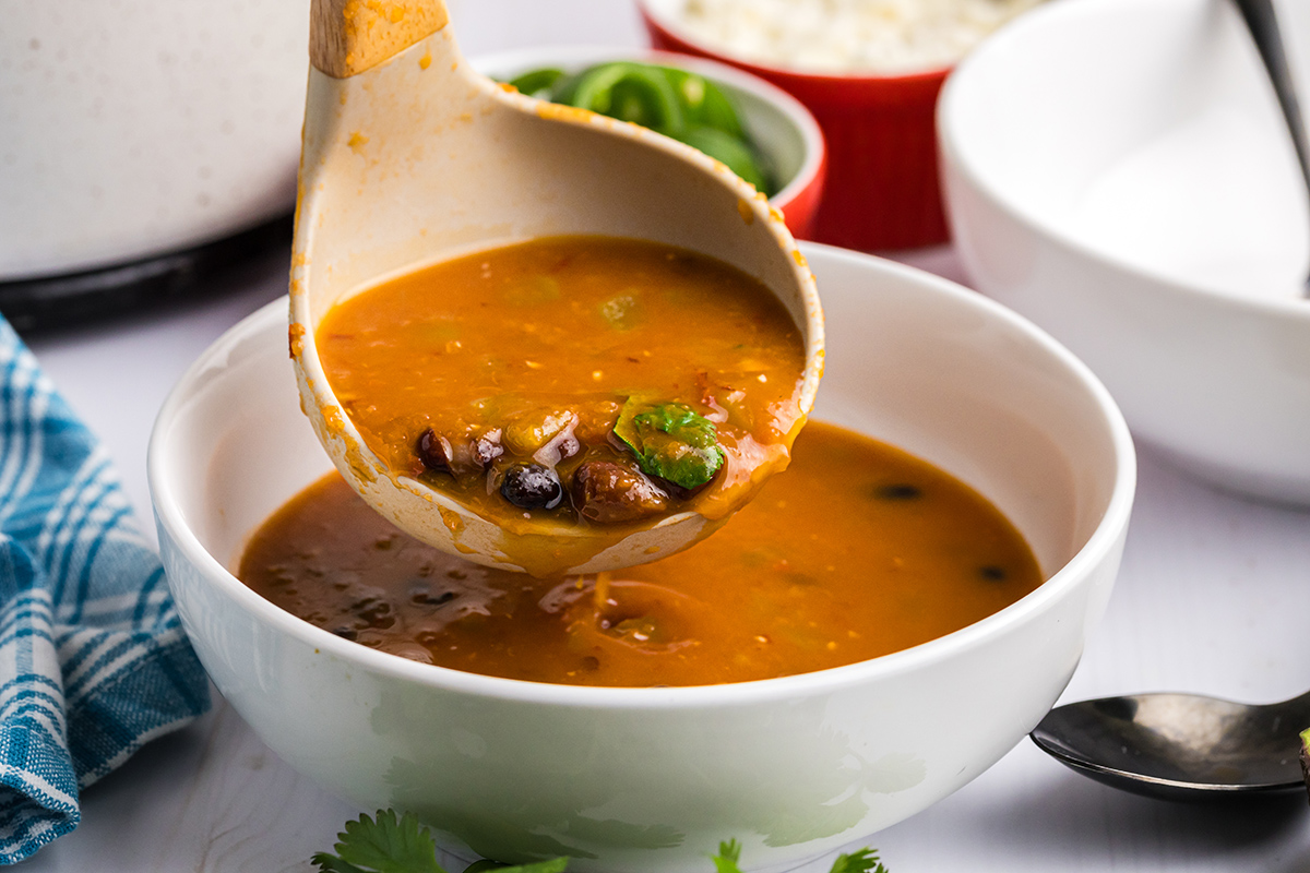 ladle adding black bean soup to bowl