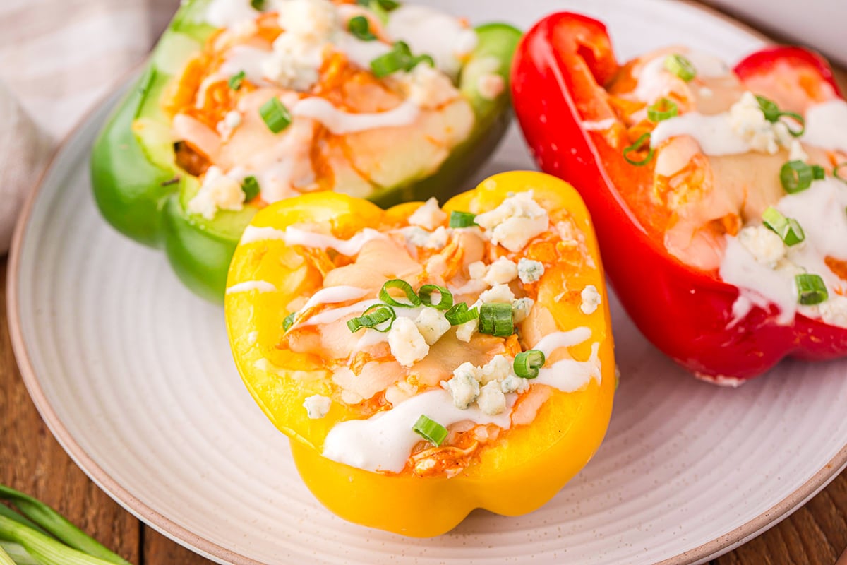 angled shot of three buffalo chicken stuffed peppers on plate