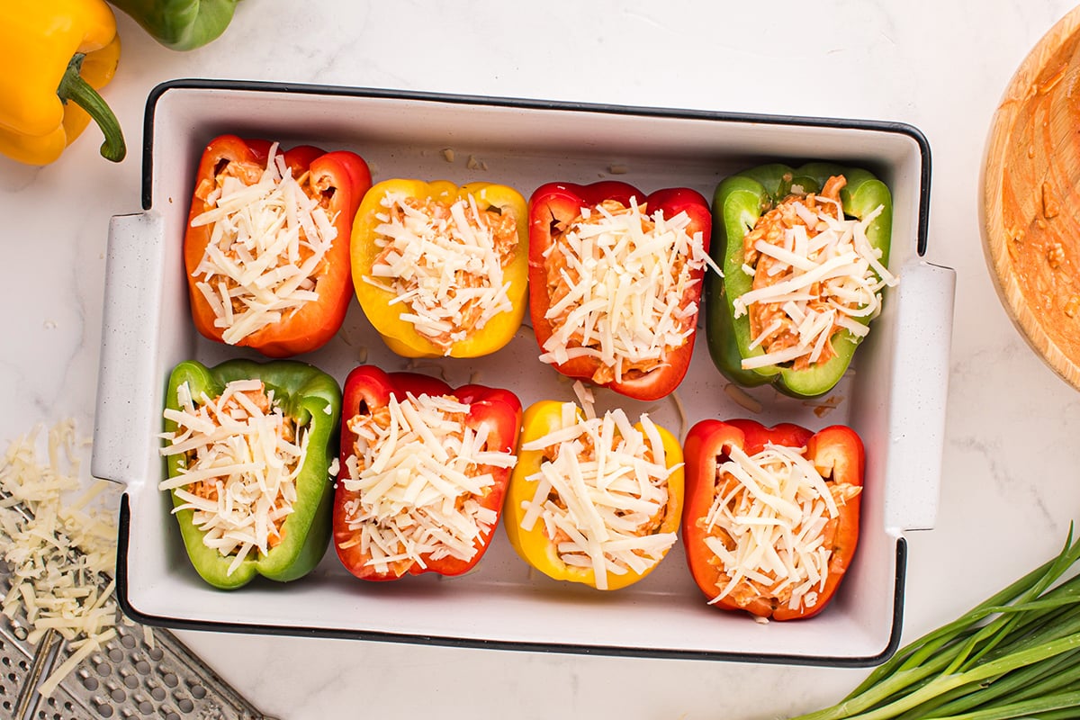 stuffed peppers topped with shredded cheese in baking dish