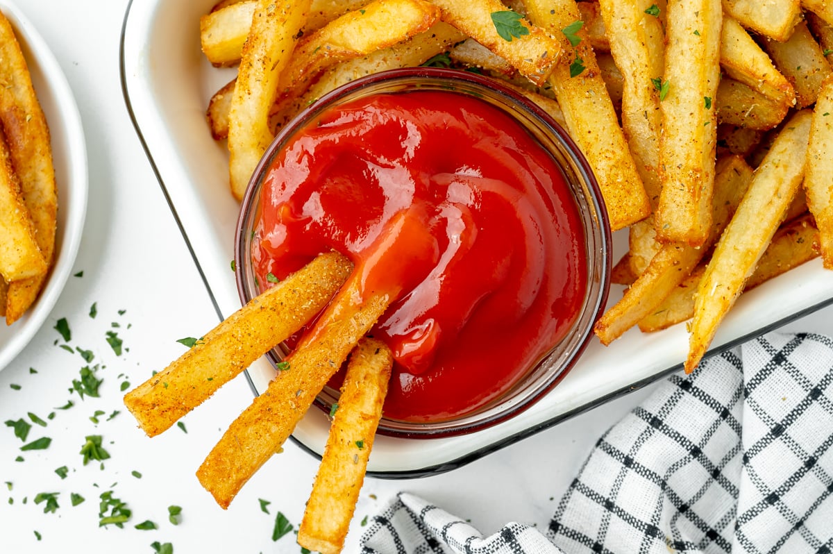 overhead shot of three cajun fries dipping into ketchup