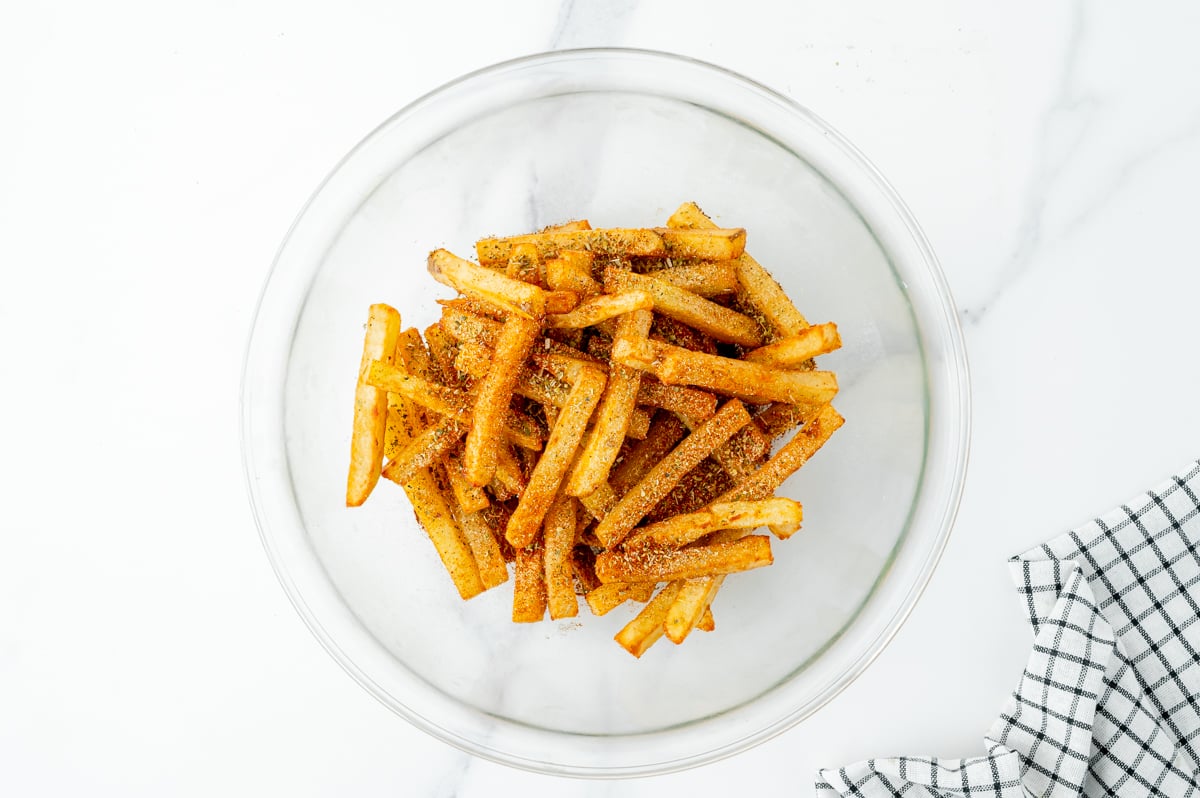 overhead shot of bowl of french fries tossed in cajun seasoning