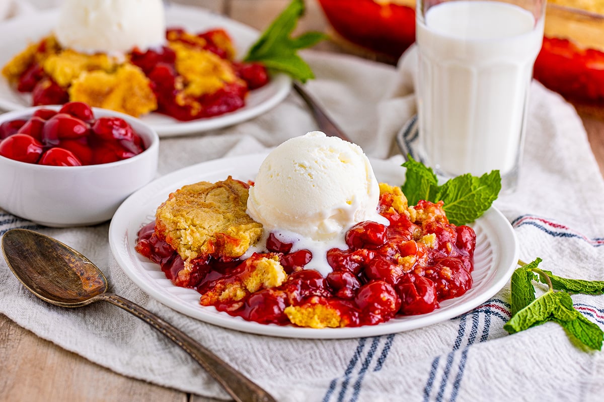 head-on shot of plated cherry dump cake with antique spoon and mint