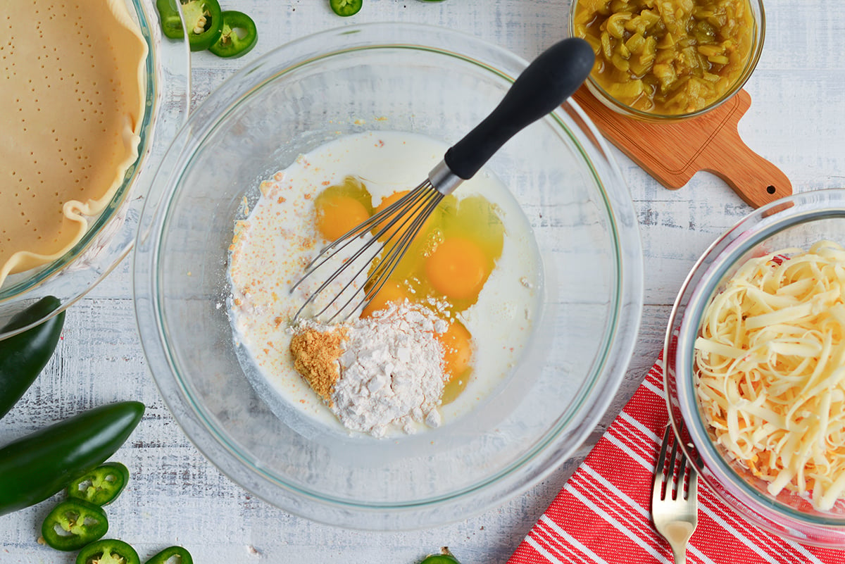 overhead shot of whisk in bowl with eggs and seasonings