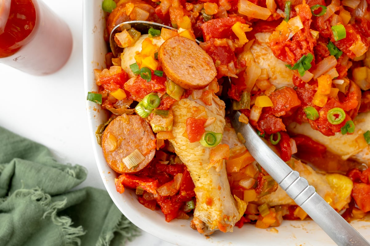 overhead shot of creole chicken on serving spoon in baking dish