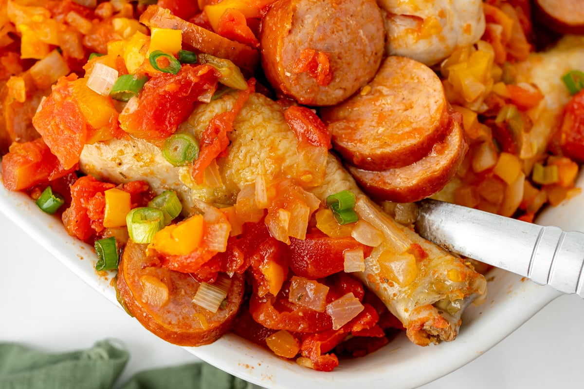 close up angled shot of serving spoon in baking dish of creole chicken