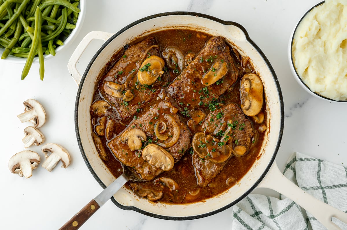 overhead shot of serving spoon in pan of cube steak