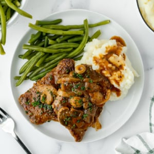 overhead shot of cube steak on plate with mashed potatoes and green beans