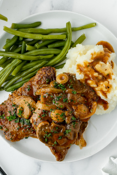 overhead shot of cube steak on plate with mashed potatoes and green beans