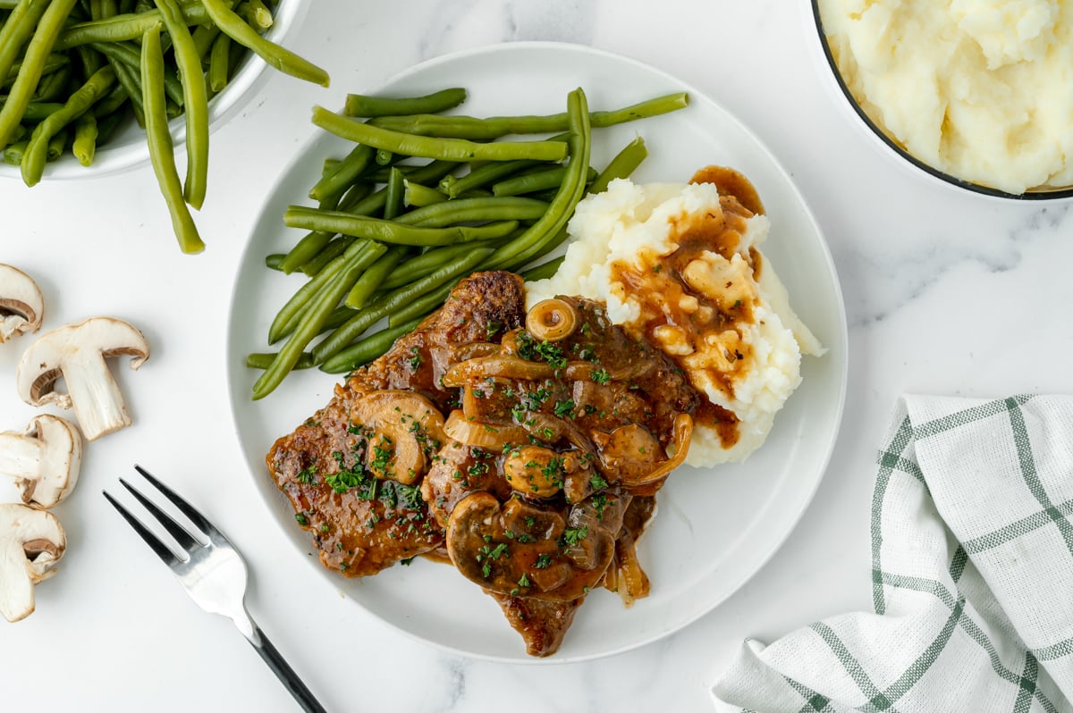 overhead shot of cube steak on plate with mashed potatoes and green beans