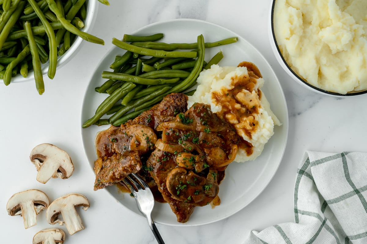 overhead shot of plate with cube steak, mashed potatoes and green beans