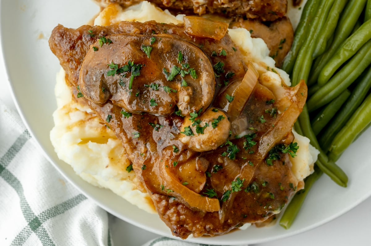 close up overhead shot of cube steak over mashed potatoes with green beans