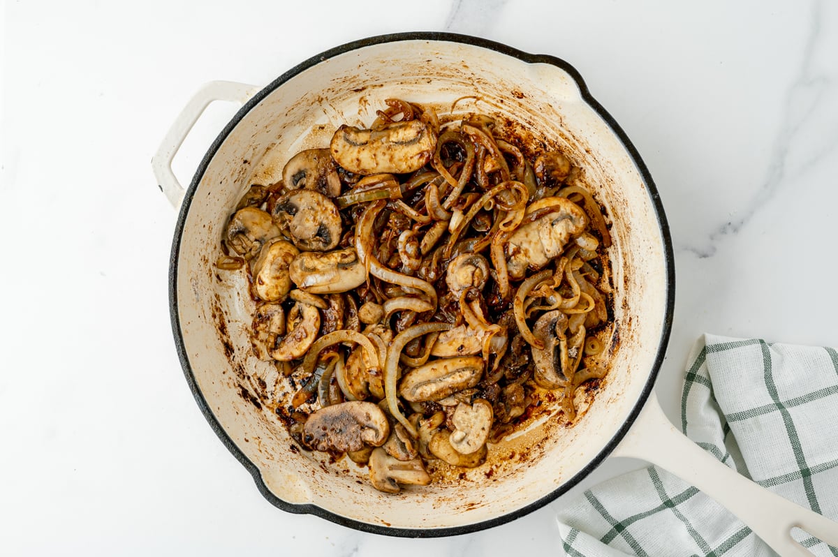 overhead shot of onions and mushrooms cooking in pan