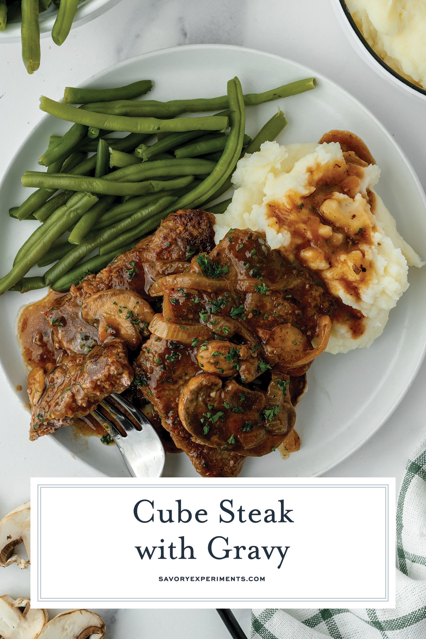 overhead shot of plate of cube steak with mashed potatoes and green beans with text overlay