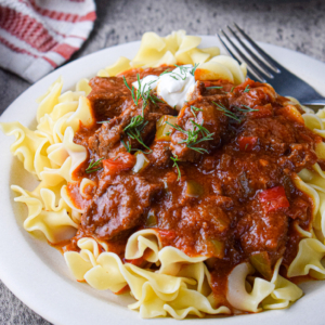 angled shot of beef paprikash over noodles