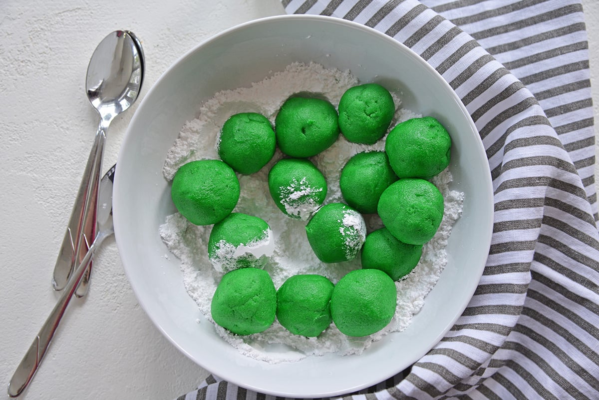 green cookie dough balls in powdered sugar