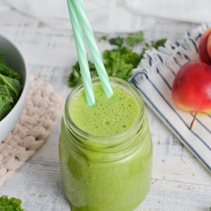 angled shot of green smoothie with two straws