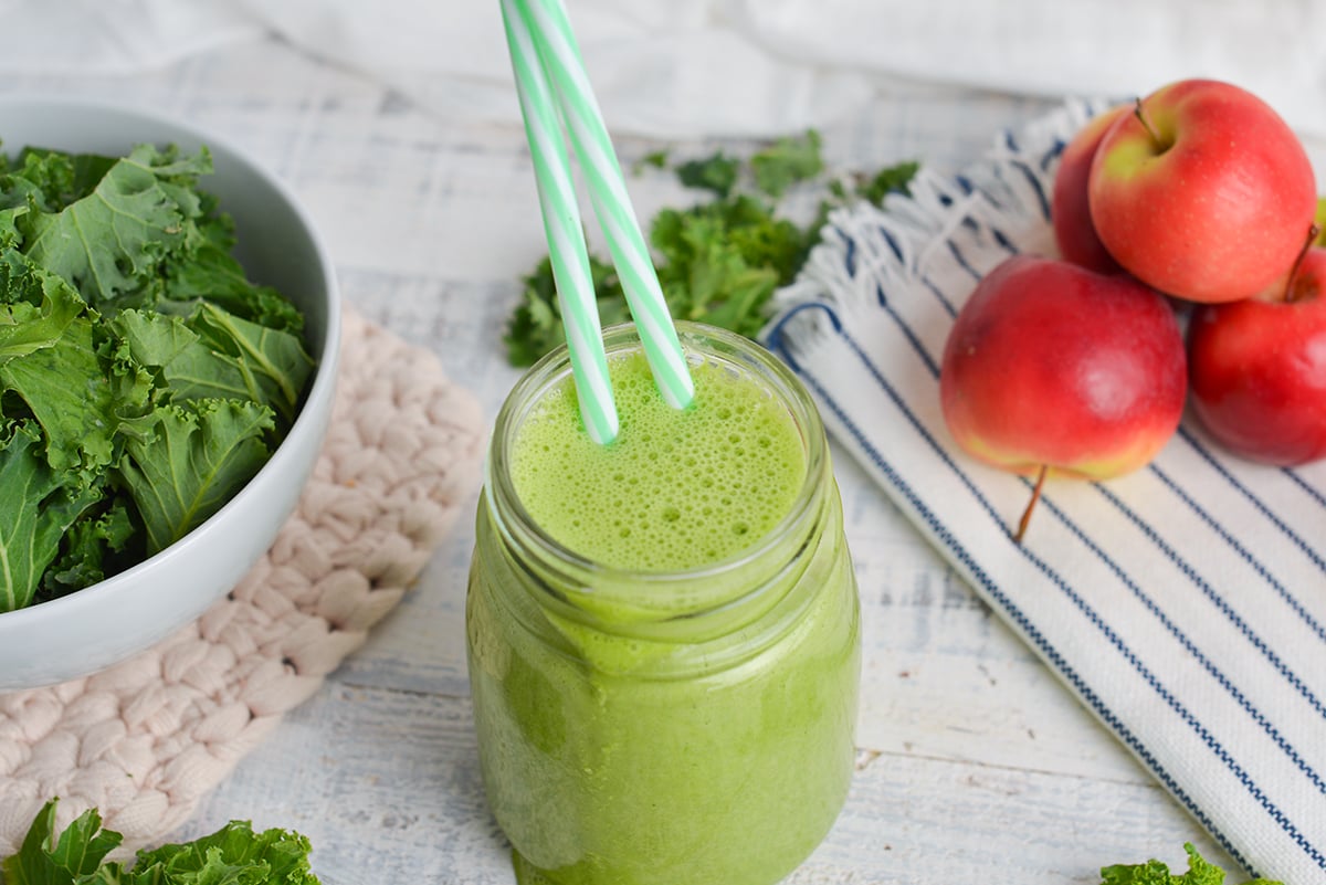 angled shot of green smoothie with two straws