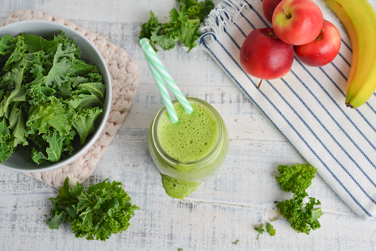 overhead shot of green smoothie with two straws