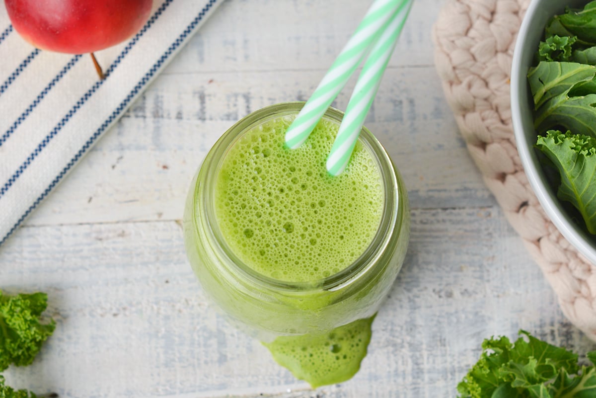 close up overhead shot of green smoothie with two straws