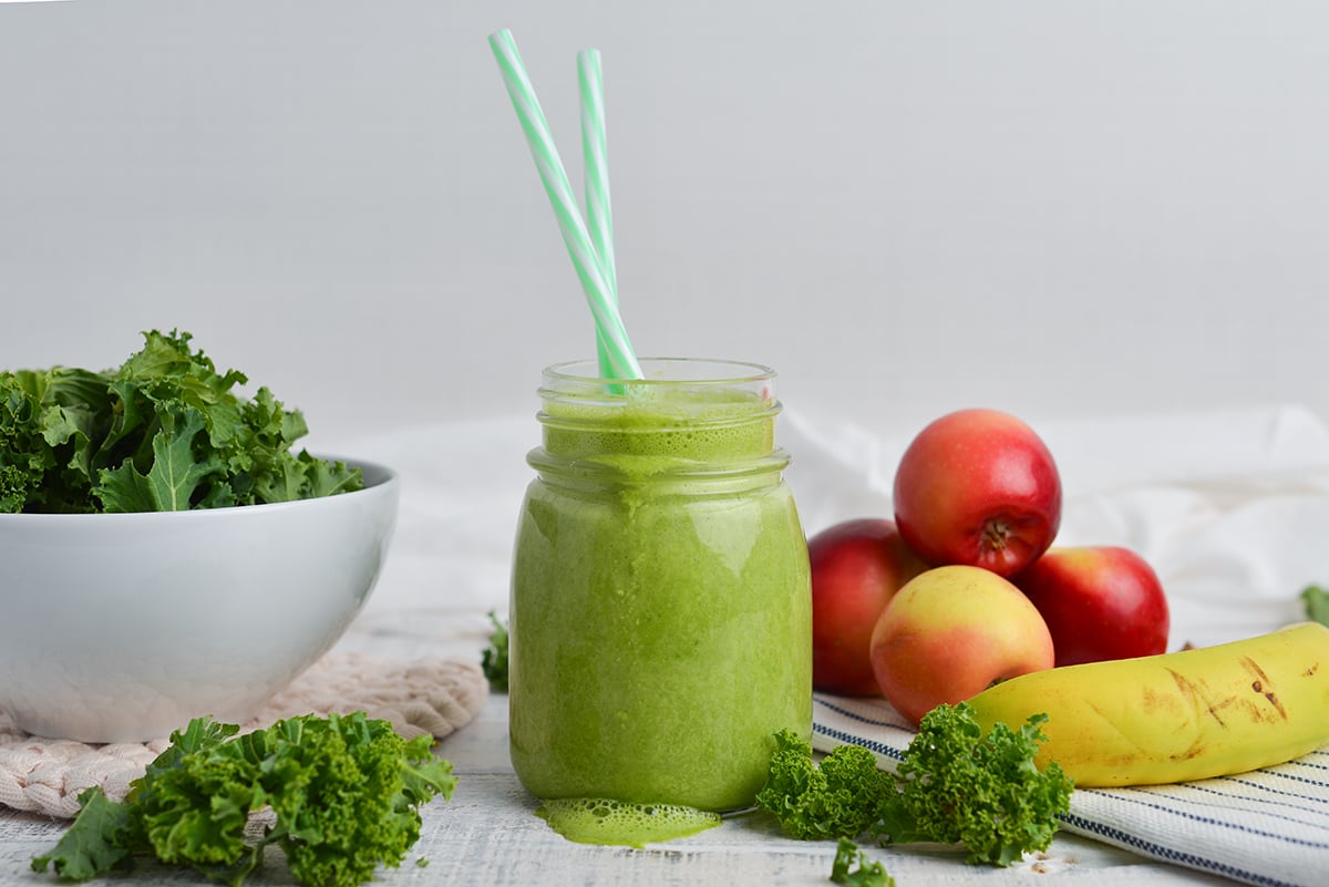 straight on shot of green smoothie with two straws