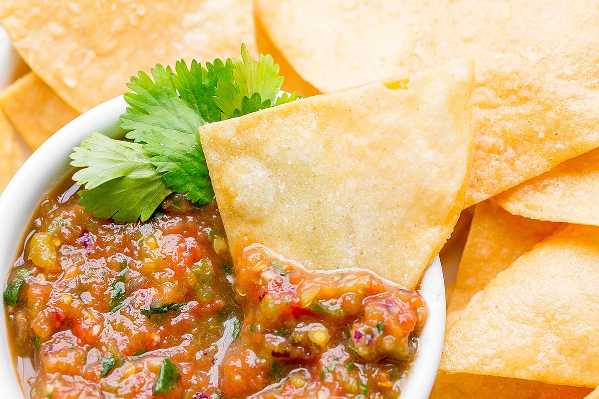 close up overhead shot of tortilla chip in bowl of salsa